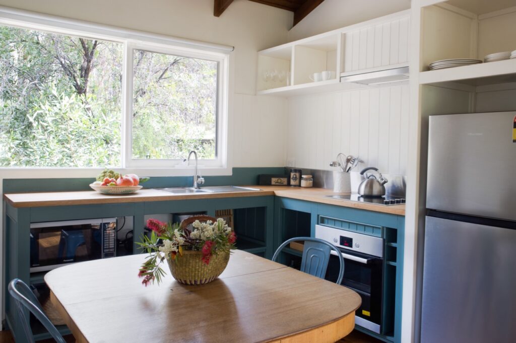 This inviting space at the Best Accommodation Blue Mountains features open shelves displaying dishes and views of greenery outside. | Werriberri
